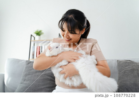Happy Woman Playing with Cat in Cozy Living Room at Home. 108770228