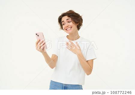 Portrait of girl talking on mobile phone, video chats with friends on smartphone, standing over white studio background Portrait of girl talking on mobile phone, video chats with friends on smartphone, standing over white studio background 108772246