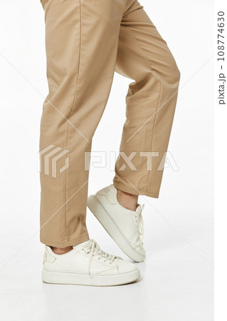 man wearing white sneakers and casual beige pants on studio background. side view man wearing white sneakers and casual beige pants on studio background. side view 108774630