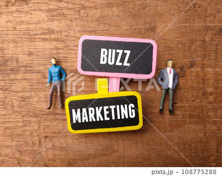 Wooden board and miniature people with text BUZZ MARKETING on a wooden background. Wooden board and miniature people with text BUZZ MARKETING on a wooden background. 108775288
