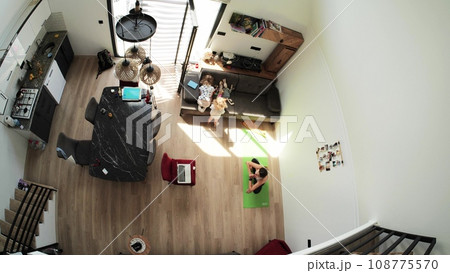 Kids play while their mom attends an online yoga class at home, overhead view 108775570