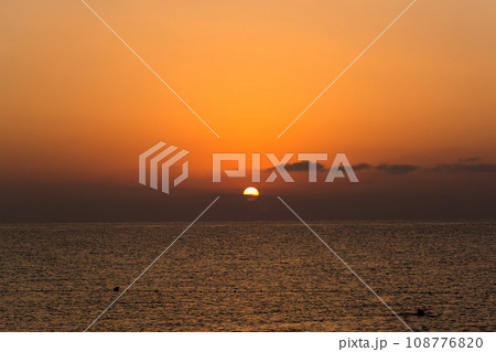 Sunset over the sea with rare floating people in the water 108776820