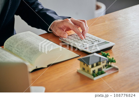 六法全書を見ながら電卓で計算をする男性弁護士 六法全書を見ながら電卓で計算をする男性弁護士 108776824
