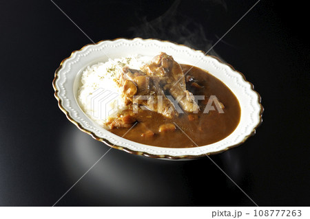 骨付きチキンの入った熱々カレーライスを黒背景で撮影 108777263