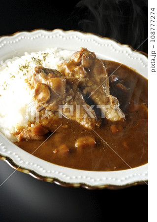 骨付きチキンの入った熱々カレーライスを黒背景で撮影 108777274