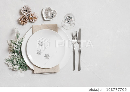 Festive table setting with Christmas silver decorations on white background. New Year serving with a copy space. Copy space, top view, flat lay. 108777706