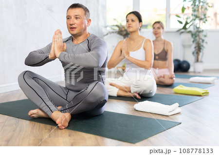 Group different nationality people practise yoga, meditation in lotus position in fitness center Group different nationality people practise yoga, meditation in lotus position in fitness center 108778133