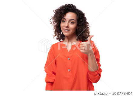 young successful european woman with curly black hair keeps dressed in a bright orange blouse 108778404