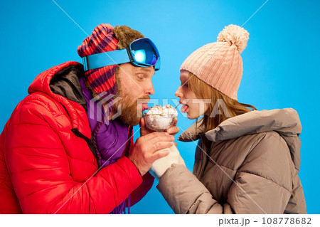 Close up side view portrait of funny cute teenager, kid and father, dad dressed warming clothes eating sweet cream isolated blue studio background. 108778682