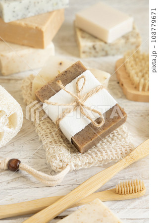 Beige handmade soap bar on soap saver bag near hygiene Items close up 108779671