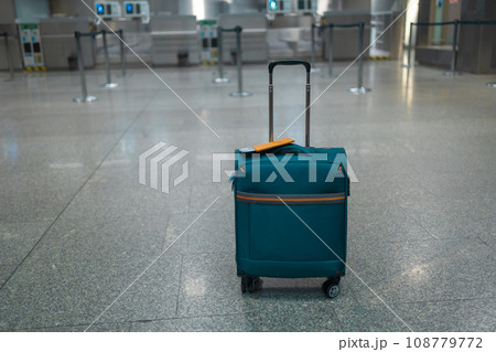 Blue suitcase in an empty airport hall, traveler cases in the departure airport terminal waiting for the area, vacation concept, blank space for text message or design 108779772
