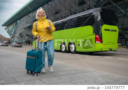 Tourist is waiting a taxi. Senior woman stand outside airport and wait for taxi cab after vacation or travel.  108779777