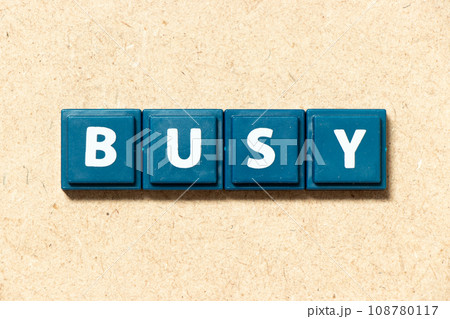 Tile alphabet letter in word busy on wood background Tile alphabet letter in word busy on wood background 108780117