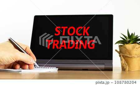Stock trading symbol. Concept words Stock trading on beautiful black tablet. Beautiful white background. Businessman hand. Business stock trading concept. Copy space. Stock trading symbol. Concept words Stock trading on beautiful black tablet. Beautiful white background. Businessman hand. Business stock trading concept. Copy space. 108780204