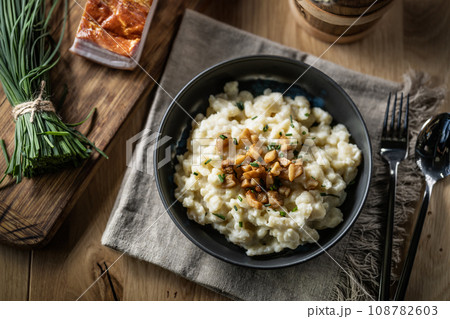 Halusky as traditional Slovak potato gnocchi with sheep cheese bryndza, fried bacon and chives 108782603
