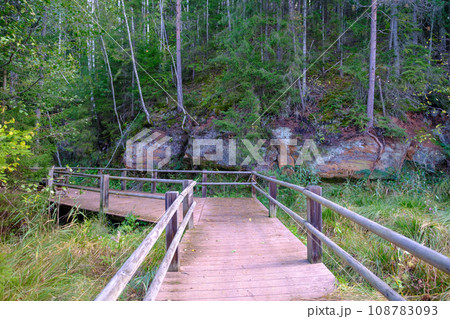 A wooden bridge, a path with a railing as a place for tourists to walk to an environmental object that is difficult to access. Red sand cliffs. Autumn in Latvia A wooden bridge, a path with a railing as a place for tourists to walk to an environmental object that is difficult to access. Red sand cliffs. Autumn in Latvia 108783093