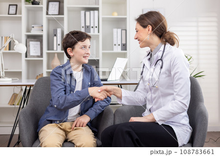 Teenager boy patient and female doctor shaking hands, successful reception consultation in bright office of friendly clinic, health concept, professional doctor Teenager boy patient and female doctor shaking hands, successful reception consultation in bright office of friendly clinic, health concept, professional doctor 108783661