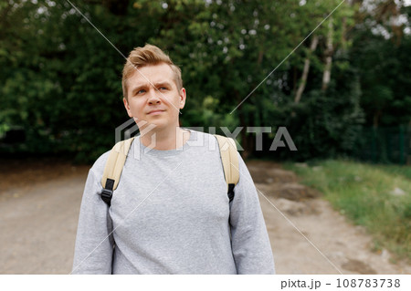 Lonely 30s man on road, concept of loneliness, depression, thoughtfulness. Male hipster Traveler with backpack. Man in active trekking clothes walking in the countryside, High quality photo 108783738