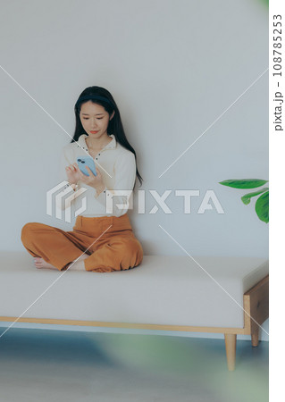 ソファーに座ってスマホを弄る若い女性 ソファーに座ってスマホを弄る若い女性 108785253