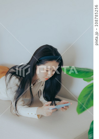 ソファーに座ってスマホを弄る若い女性 ソファーに座ってスマホを弄る若い女性 108785256