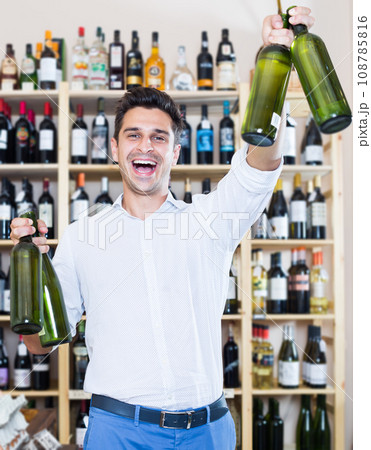 Smiling man holding wine bottles in winery section Smiling man holding wine bottles in winery section 108785816