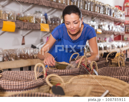 woman taking dried beans with shovel from backet in organic shop woman taking dried beans with shovel from backet in organic shop 108785911
