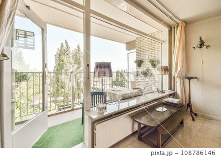 a living room with a desk and chair in front of the window looking out onto the patio area to the trees outside a living room with a desk and chair in front of the window looking out onto the patio area to the trees outside 108786146