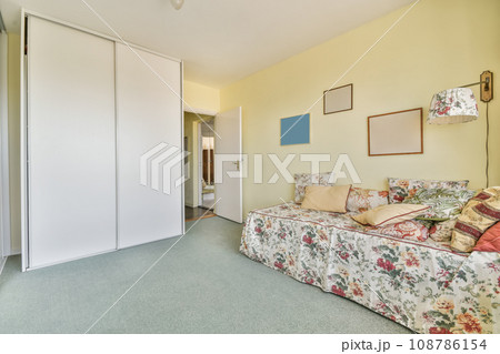 a living room with yellow walls and floral bed spread across the room, there is an open door leading to another room 108786154