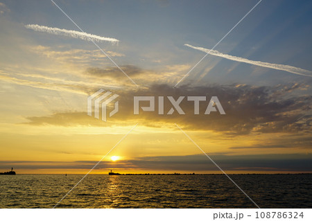 A beautiful multicolor golden sunset on the shore of the Baltic Sea, golden sunset on the seashore 108786324