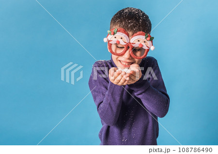 Child boy holds snow on blue background. Christmas and New Year holidays concept. Generation alpha and gen alpha children. Copy space Child boy holds snow on blue background. Christmas and New Year holidays concept. Generation alpha and gen alpha children. Copy space 108786490