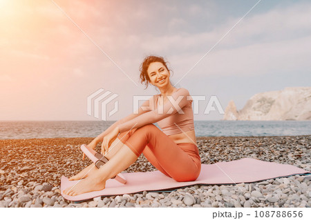 Woman sea pilates. Sporty happy middle aged woman practicing fitness on beach near sea, smiling active female training with ring on yoga mat outside, enjoying healthy lifestyle, harmony and meditation Woman sea pilates. Sporty happy middle aged woman practicing fitness on beach near sea, smiling active female training with ring on yoga mat outside, enjoying healthy lifestyle, harmony and meditation 108788656