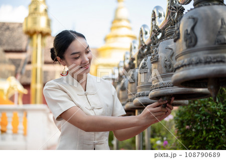 Beautiful Thai-Asian woman in a traditional Thai-Northern dress is ringing temple bells in a temple. 108790689