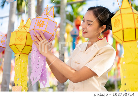 A beautiful Thai-Asian woman is hanging a paper lantern and enjoying YI Peng festival at a temple. 108790714