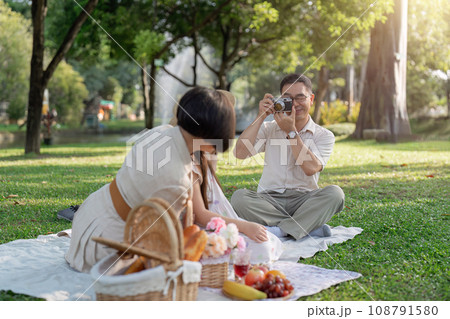 happy smiling family grandparent and grandchild picnic together outside at park 108791580