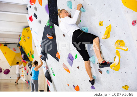 Woman exercising in climbing gym Woman exercising in climbing gym 108791669