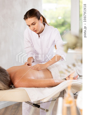 Young woman doing back massage to elderly woman Young woman doing back massage to elderly woman 108791918