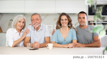 Portrait of a happy family of four sitting together at kitchen table 108791923
