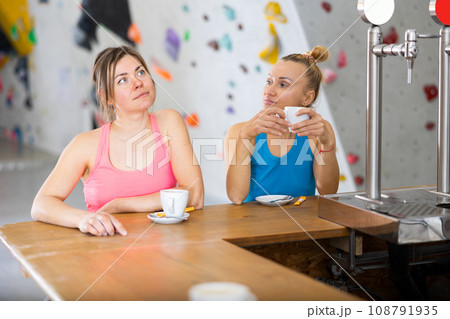Two women drinking tea and chatting during break in bouldering gym Two women drinking tea and chatting during break in bouldering gym 108791935