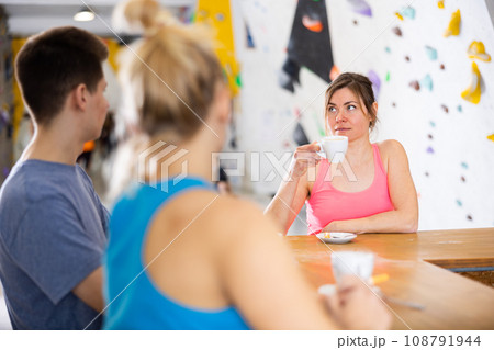 Two sports women and a guy drink tea or coffee after training at climbing wall 108791944