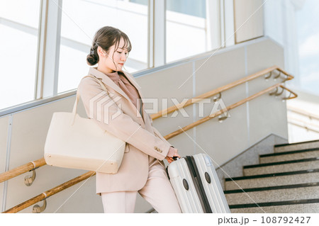 階段で重い荷物を持つ女性(駅・空港) 階段で重い荷物を持つ女性(駅・空港) 108792427