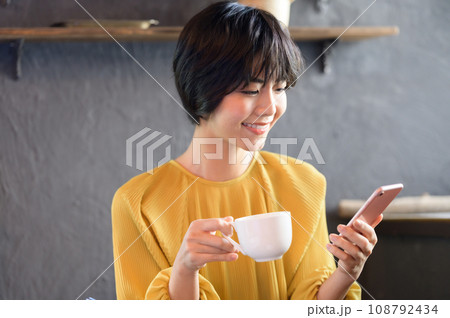 カフェでコーヒーを飲みながらスマホを見る女性 撮影協力「洋菓子店 sentiment」 カフェでコーヒーを飲みながらスマホを見る女性 撮影協力「洋菓子店 sentiment」 108792434