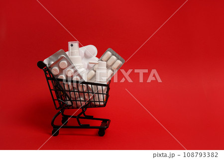 Black shopping cart with pills on red background, copy space. Medicine concept, online shopping, black friday 108793382