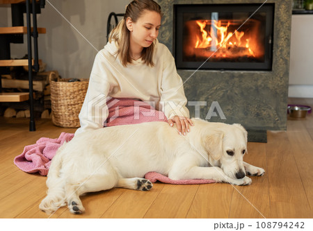 Woman sitting with dog near fireplace Woman sitting with dog near fireplace 108794242