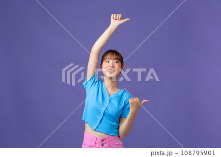 Young asian girl standing, pointing to the back behind with hand and thumbs up, smiling confident Young asian girl standing, pointing to the back behind with hand and thumbs up, smiling confident 108795901