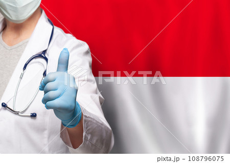 Indonesian doctor's hand showing thumb up positive gesture on flag of Indonesia background 108796075