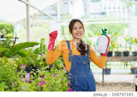 Happy Asian woman doing a gardening and taking care small plants. Female gardener watering a cactus and house plant. 108797165
