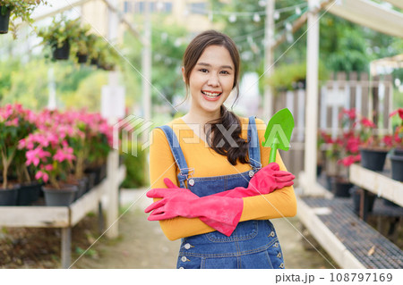 Happy Asian woman doing a gardening and taking care small plants. Female gardener watering a cactus and house plant. Happy Asian woman doing a gardening and taking care small plants. Female gardener watering a cactus and house plant. 108797169