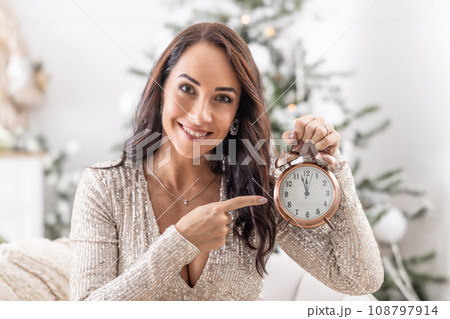 Woman pointing at the clock showing that Christmas is just around the corner Woman pointing at the clock showing that Christmas is just around the corner 108797914