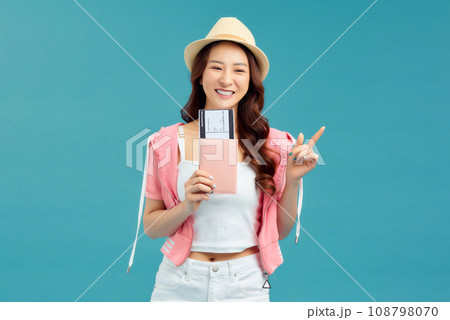 Happy Asian woman traveler with passport and boarding pass ticket isolated on blue background Happy Asian woman traveler with passport and boarding pass ticket isolated on blue background 108798070
