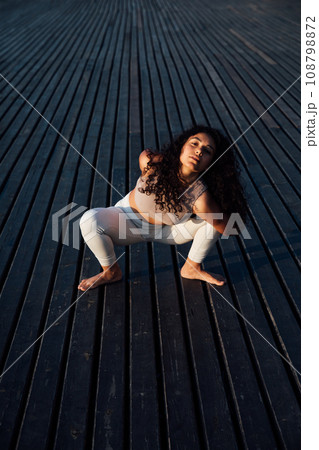Full length portrait of a middle aged woman doing yoga or pilates on a mat outside in a park.Pose chakravakasana. Full length portrait of a middle aged woman doing yoga or pilates on a mat outside in a park.Pose chakravakasana. 108798872